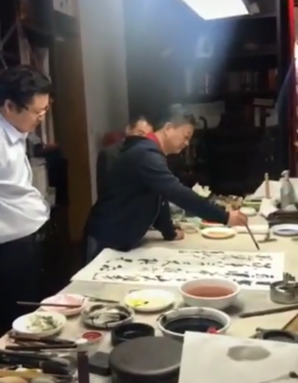 56岁朱军现身聚会，大佬聊天他指点人书法，一幅画曾卖130万